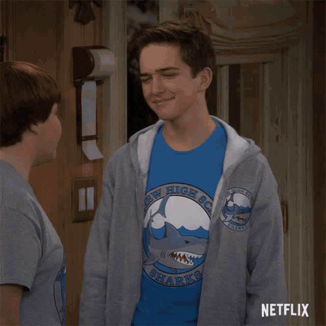 a boy wearing a shirt that says new high school sharks on it