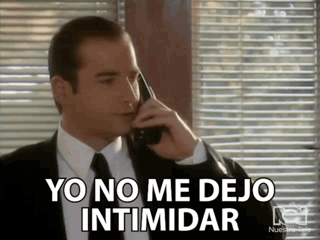 a man in a suit and tie talking on a cell phone with yo no me dejo intimidar written on the bottom
