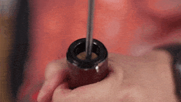a person is holding a corkscrew in their hand and opening a wine bottle .