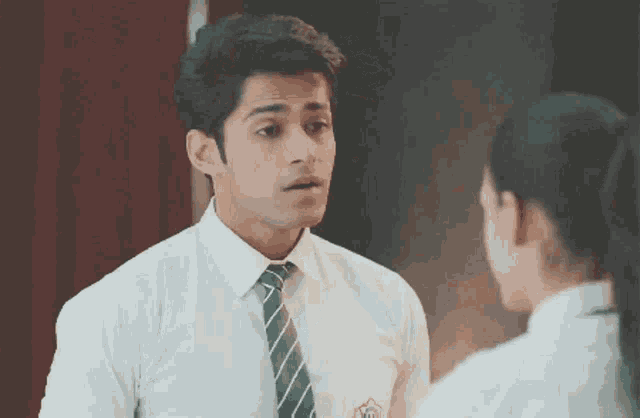 a man in a white shirt and green tie is looking at a woman