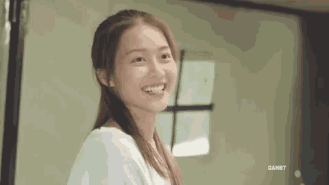 a woman in a white shirt is smiling and looking at the camera .