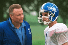 a man wearing a blue jacket with the number 3 on it talks to a football player