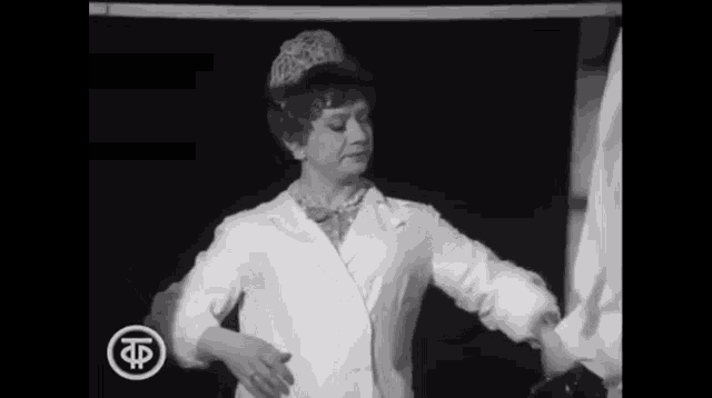 a black and white photo of a woman wearing a white coat and a hat .