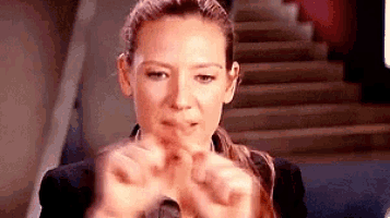 a woman is making a heart with her hands in front of a staircase .