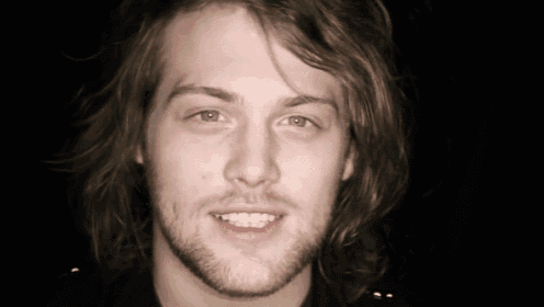 a young man with long hair and a beard is smiling
