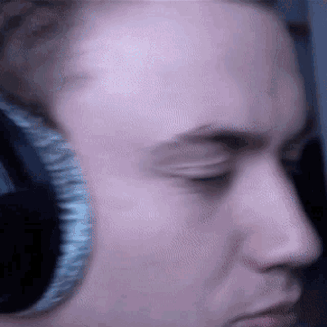 a close up of a man wearing headphones looking down