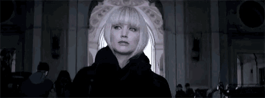 a woman with blonde hair and bangs is standing in a dark room .