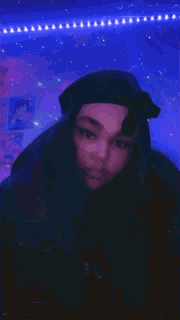 a girl wearing a black hat is standing in front of a purple background
