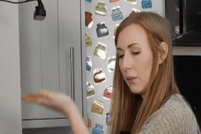 a woman sitting in front of a refrigerator with a sticker on it that says ' milk '