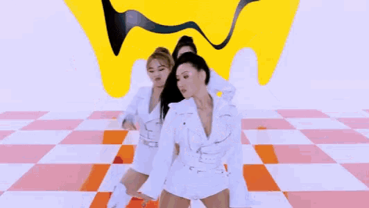 a group of women in white clothes are dancing on a checkered floor .