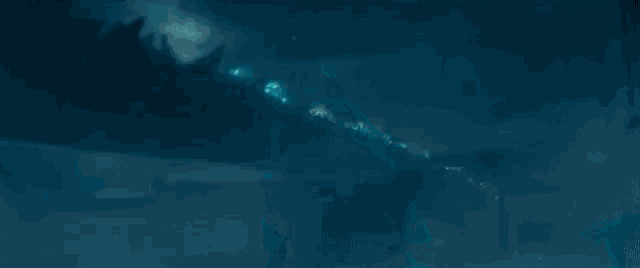 a close up of a monster in the water with a blue light coming out of it 's mouth .