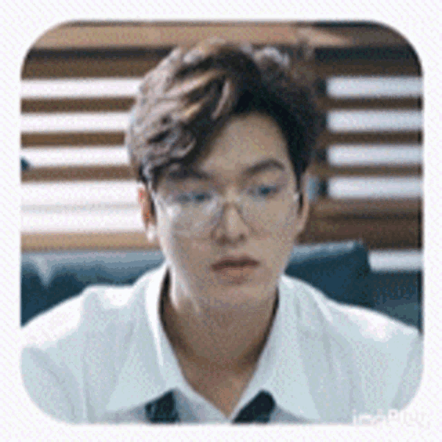a young man wearing glasses and a white shirt is sitting in a chair