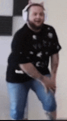 a man wearing headphones and a cat ear shirt is dancing in a room .