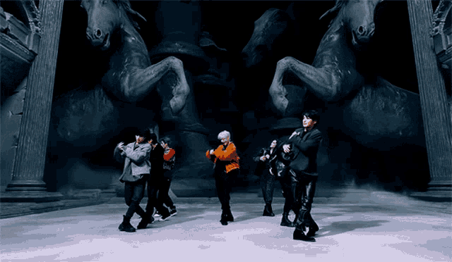 a group of people are dancing in front of a statue of horses