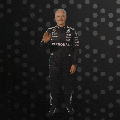a man in a petronas racing suit waves his hand