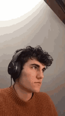 a young man wearing headphones and a sweater is making a funny face .