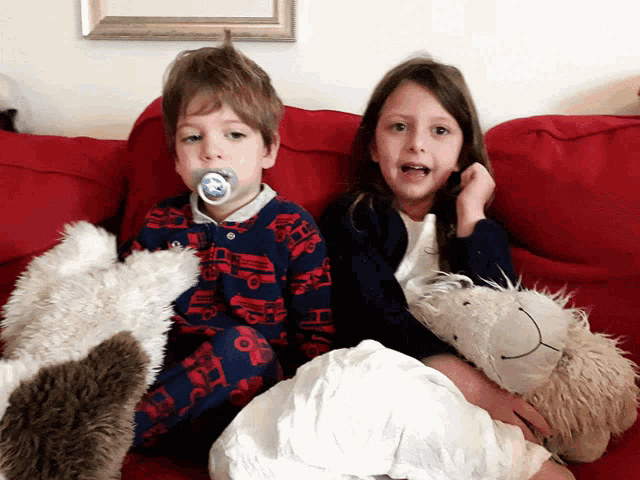 a boy and a girl are sitting on a red couch