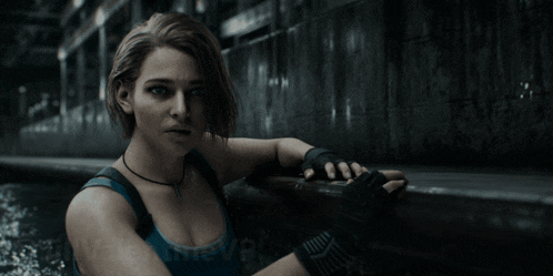 a woman in a blue tank top and black gloves is standing in a dark room with the word believe on the bottom right