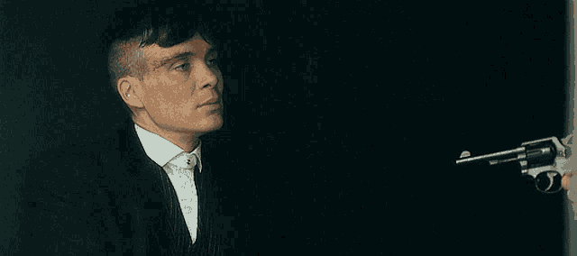 a man in a suit and tie is pointing a gun at someone .
