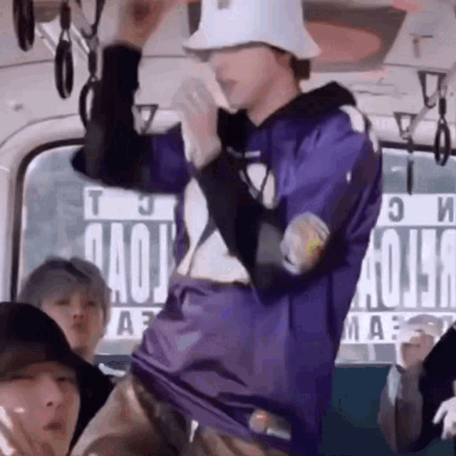 a man in a purple shirt is dancing on a bus .