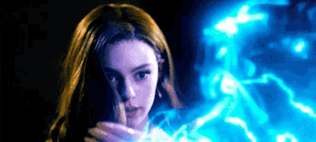 a close up of a woman holding a blue light in her hands .