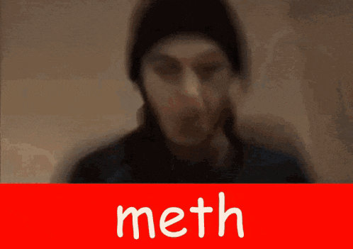 a blurry picture of a man behind a red sign that says " meth "