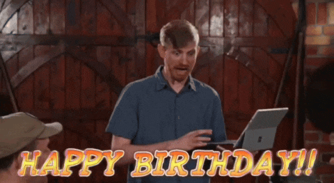 a man in a blue shirt is holding a laptop and says " happy birthday "