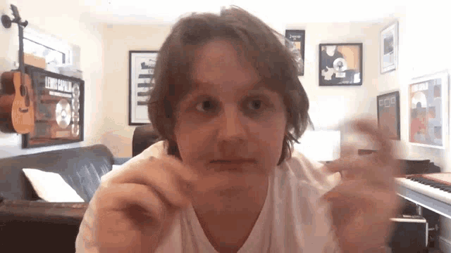 a young man in a white shirt is making a funny face in front of a piano and a couch .