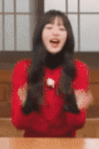 a woman in a red dress is sitting at a table with her arms outstretched .