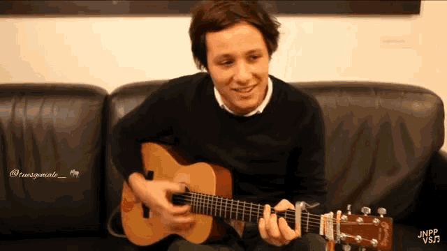 a young man is playing a guitar on a couch with the hashtag jnpp vsm