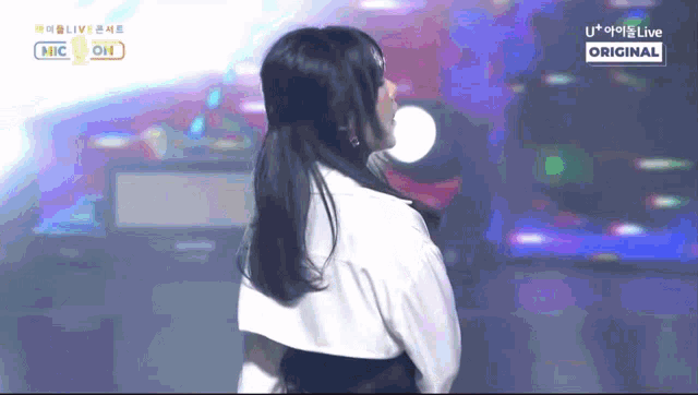 a woman stands on a stage in front of a sign that says u + live