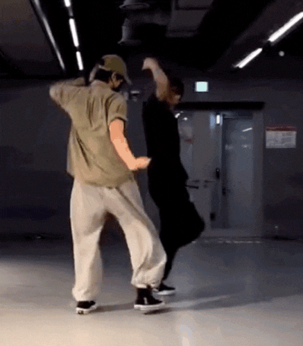 two men are dancing together in a room with a door in the background .