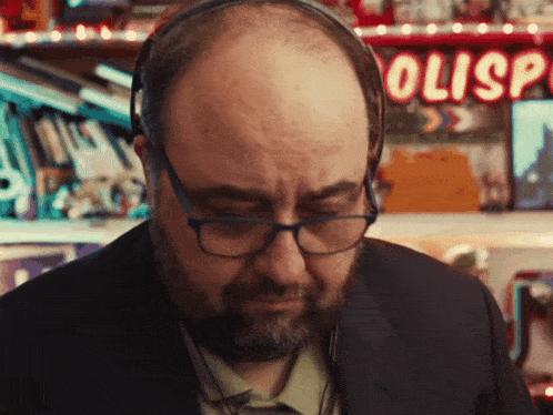 a bald man wearing glasses and headphones in front of a sign that says olisp