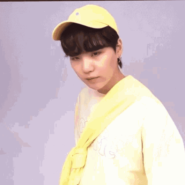 a young man wearing a yellow hat and a yellow scarf is looking at the camera .