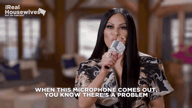 a woman is holding a microphone in front of a sign that says real housewives