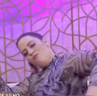 a woman is sitting in front of a pink wall .