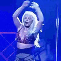 a woman in a bra is dancing on a stage in front of a blue background .