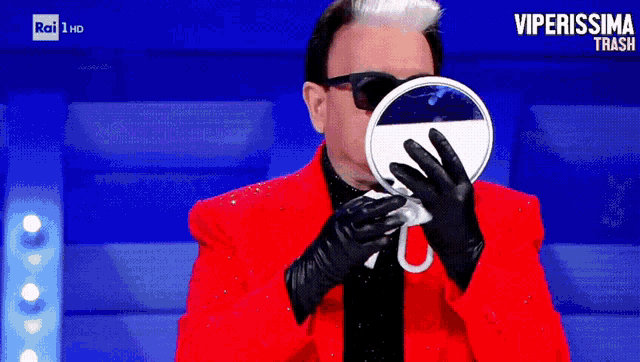 a man in a red jacket and black gloves looks at himself in a mirror with the words viperissima trash on the bottom