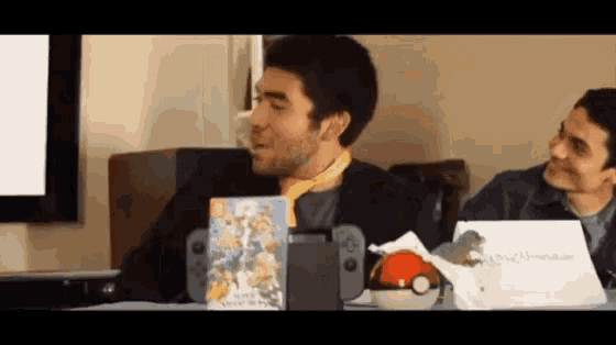 a man is sitting at a table with a nintendo switch and a game on it .