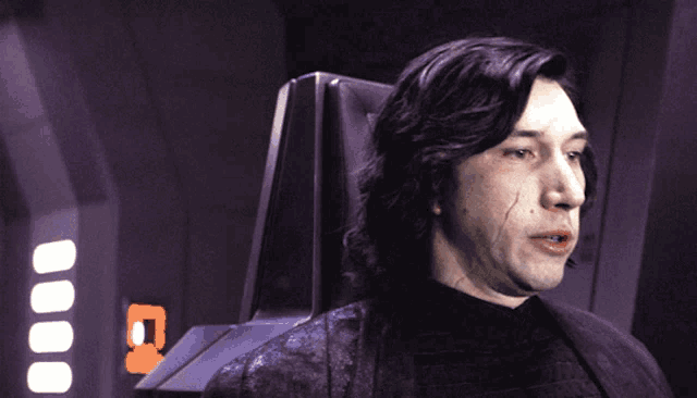 a man is sitting in a chair with a purple background