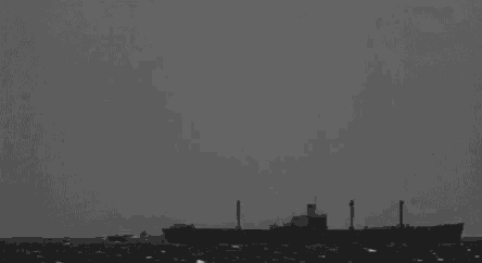 a black and white photo of a ship in the ocean surrounded by a large cloud .