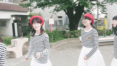 three girls wearing striped shirts and white skirts are walking in a park with a sign that says no parking