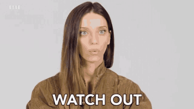 a woman in a brown jacket is making a funny face and saying `` watch out '' .