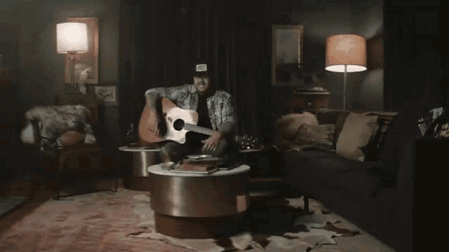 a man is playing a guitar in a dark room