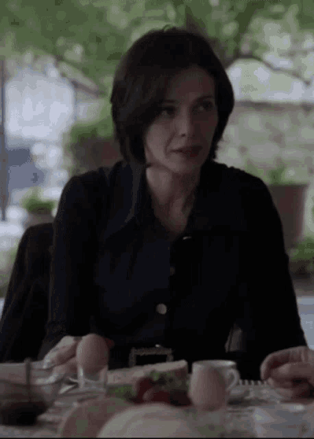 a woman in a black shirt sits at a table