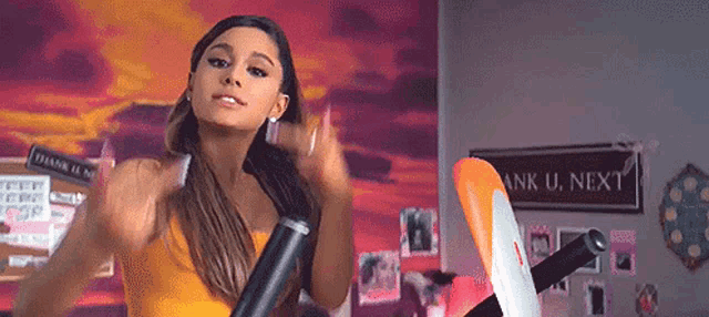 ariana grande is wearing a yellow top and riding an exercise bike .