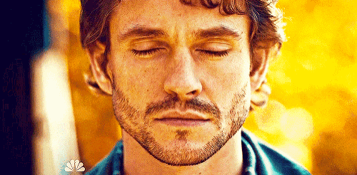 a man with a beard is sitting with his eyes closed .