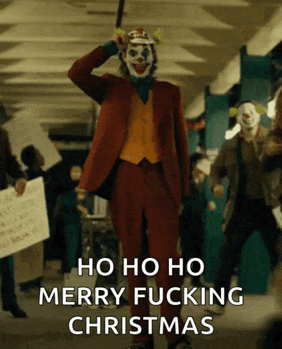 the joker says merry fucking christmas in front of a crowd of protesters