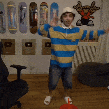 a man in a striped shirt and hat is dancing in a room .