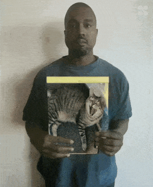 a man is holding a picture of a cat with its mouth open